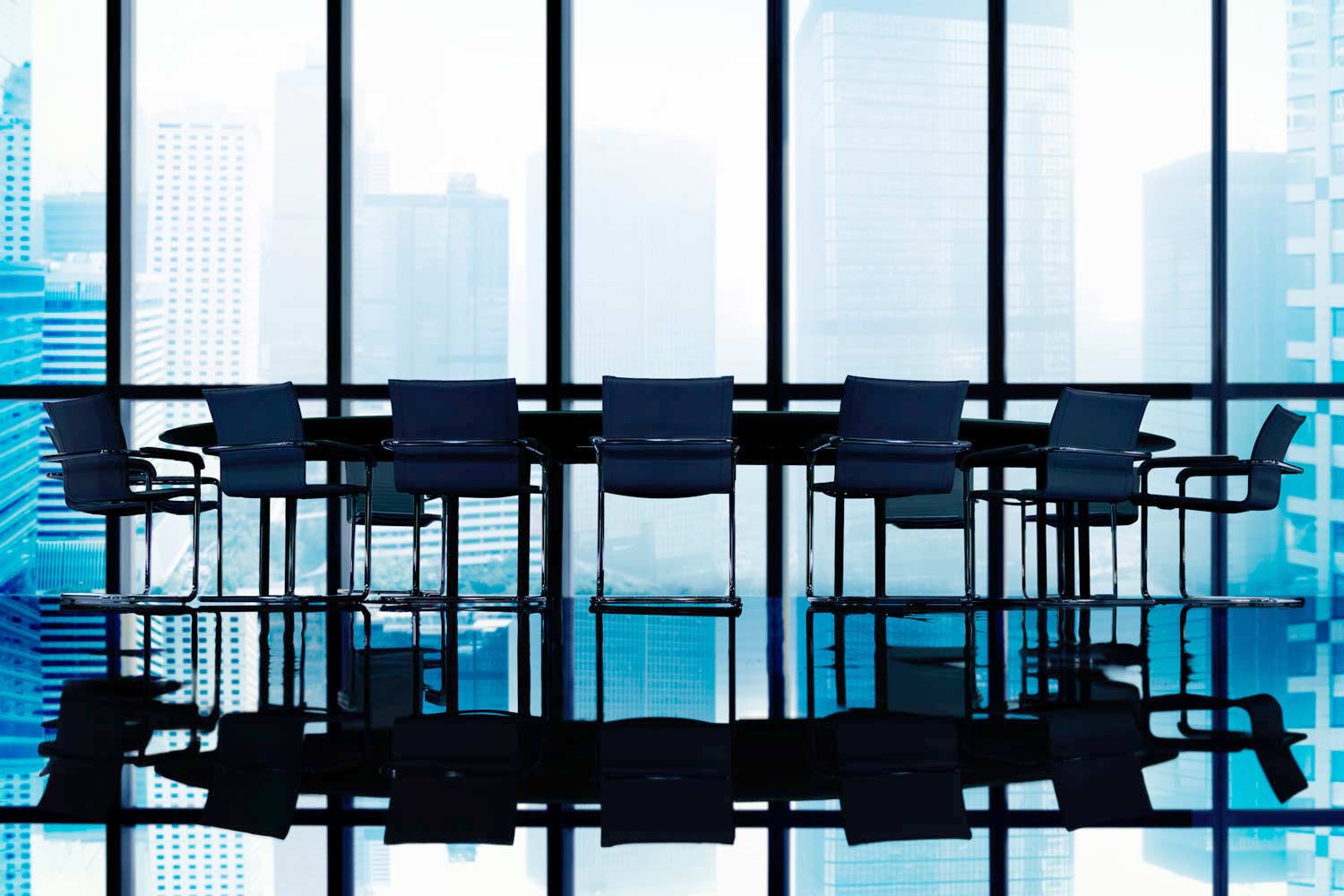 a meeting table with eight chairs in front of big glass windows overlooking city skyscrapers